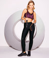 Woman wearing Freya Dynamic sports bra in Viper colour holding a jump rope against a white background